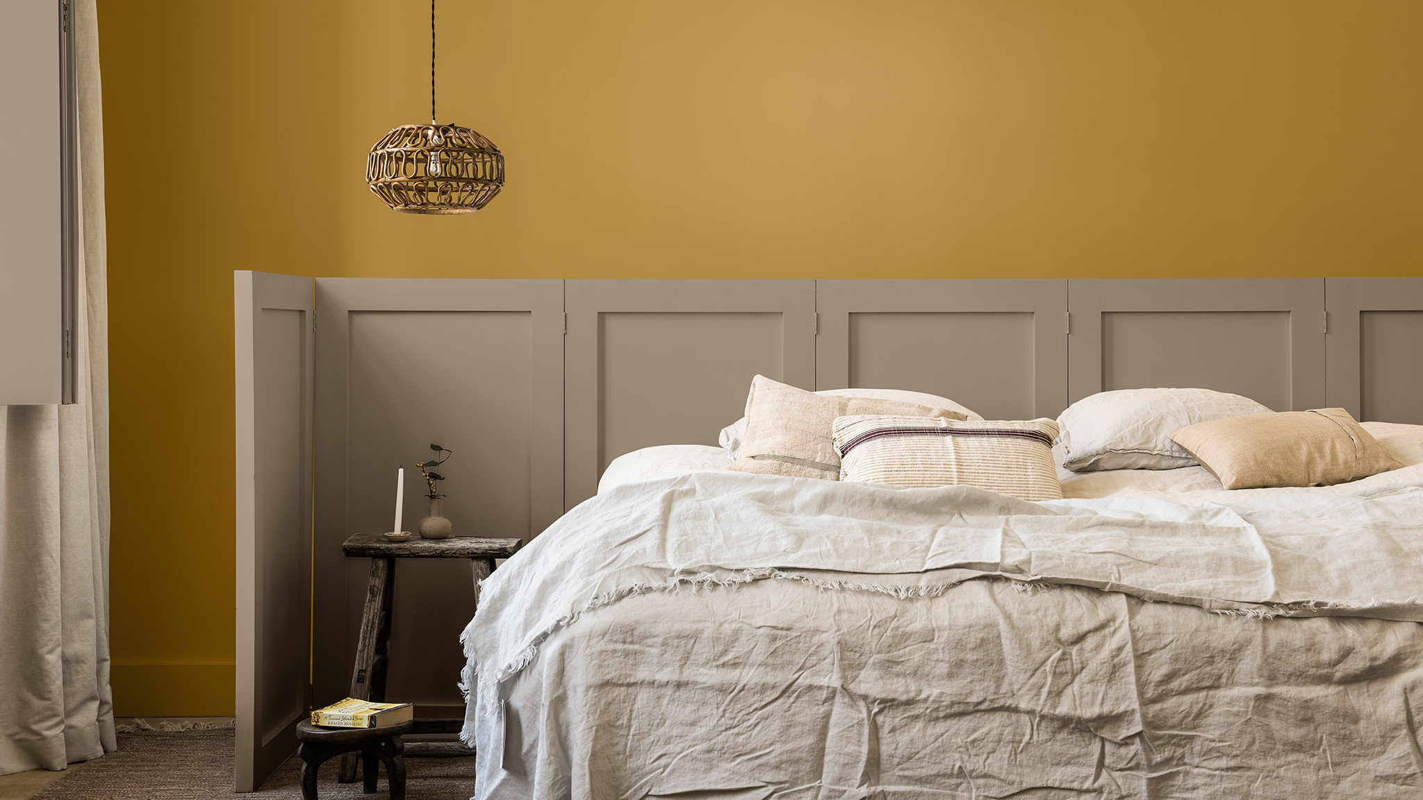 Miegamojo siena nudažyta aukso geltona spalva ir „Brave Ground“, stiklo ekranas už lovos „Dulux_CF21_ Colour_of_the_year_Timeless_colors_global_2“